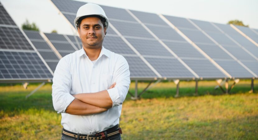 Portrait of a young Indian male engineer or architect at a solar panel farm. The concept of clean energy.