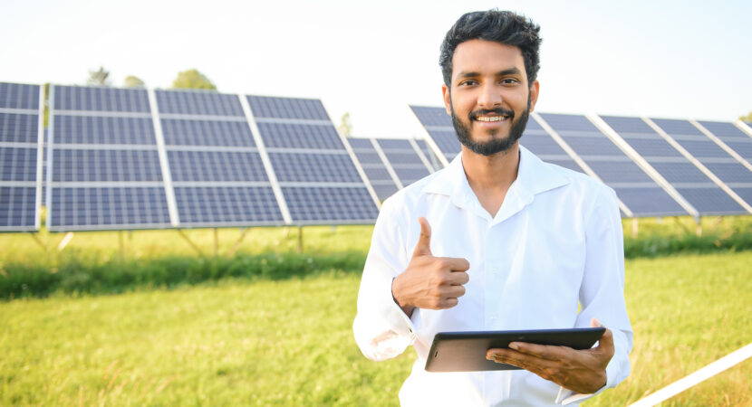 Portrait young indian technician or manager wearing formal cloths standing with solar panel. renewable energy, man standing crossed arm, copy space.